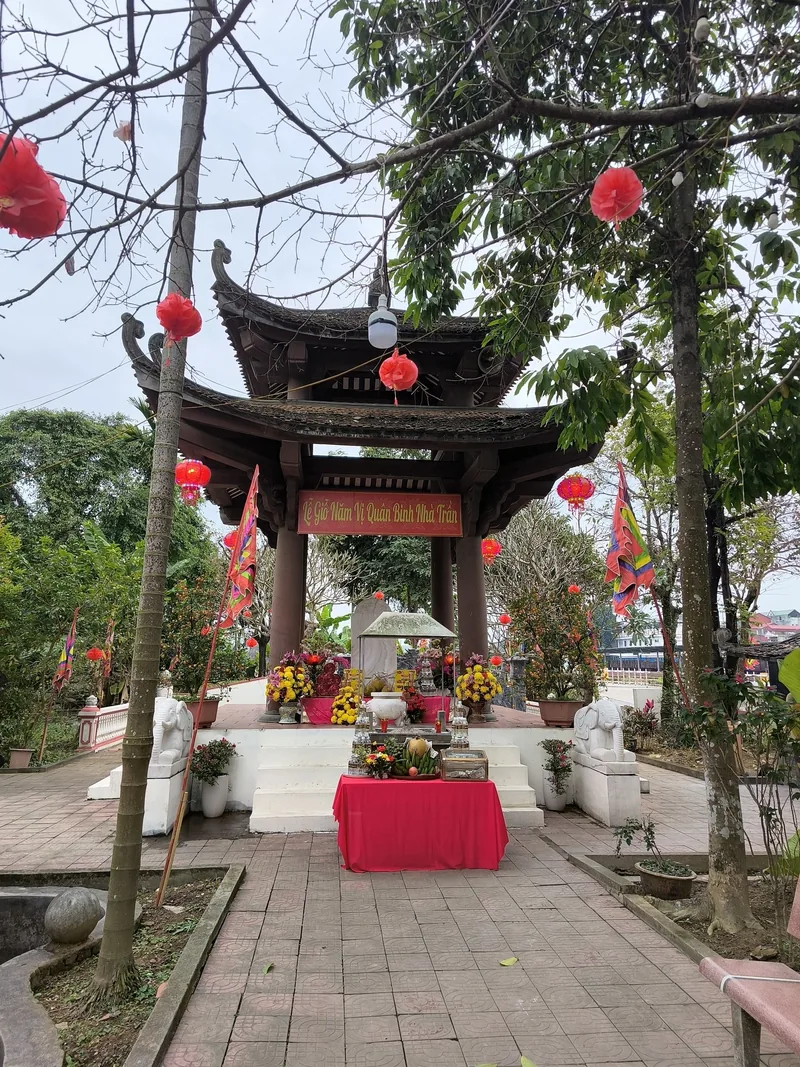 Một gian nhà gỗ thờ với đèn lồng đỏ và hoa cúng đặt trong sân đền gần Sa Pa.