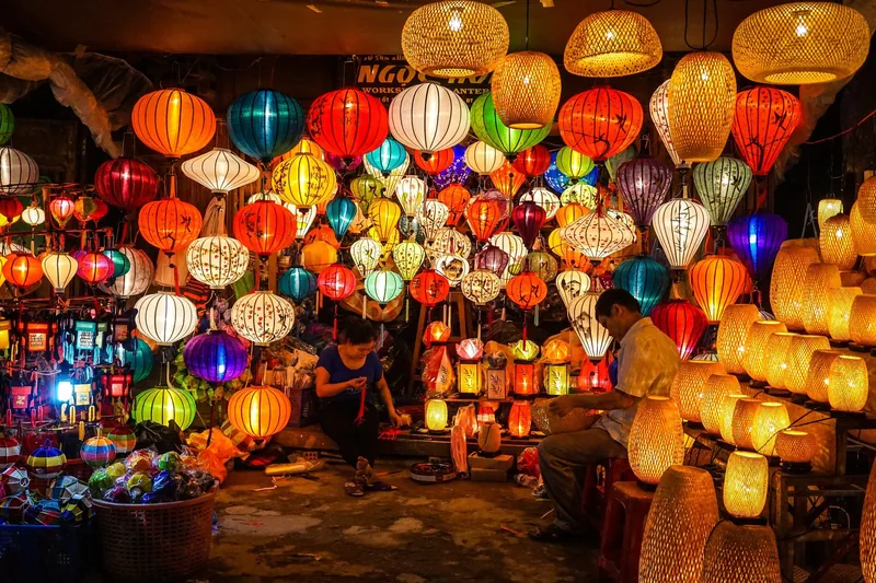 Cửa hàng đèn lồng ở Hội An rực rỡ sắc màu với hàng trăm chiếc đèn lụa và tre, người bán đang làm việc bên trong.